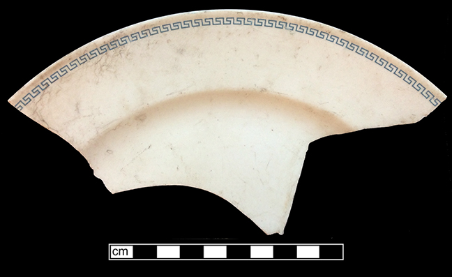 Plate. Unglazed bisque waster. Transfer printed Greek key rimmotif in blue. Rim diameter: 9.75”; 4.1 mm thick.